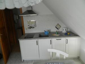 een keuken met witte kasten, een wastafel en een trap bij Ferienwohnung "Achtern Diek" 45324 in Groß Zicker