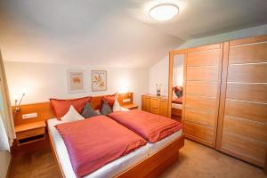 a bedroom with a large bed with an orange blanket at Ferienwohnung Sonnenbichl in Schattwald