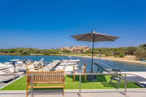 a patio with a table with an umbrella and boats at Hoceanika Houseboat Porto Rotondo in Porto Rotondo
