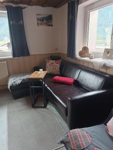 a living room with a black leather couch and a table at Haus Deule in Sankt Gallenkirch