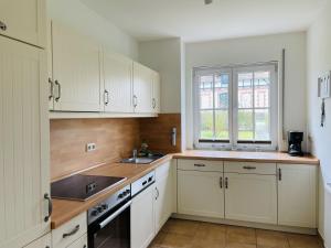 a kitchen with white cabinets and a sink and a window at Landhaus zum Strande - 44-08 in Kägsdorf