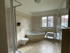 a bathroom with a tub and a toilet and a sink at Landhaus zum Strande - 44-08 in Kägsdorf