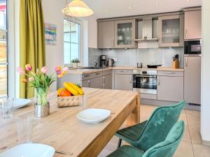 Una cocina con una mesa de madera y sillas verdes. en Windland, en Zingst
