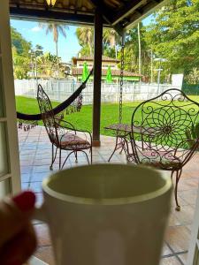 two chairs and a hammock on a porch with a swing at Sol & Aconchego Paraty in Paraty