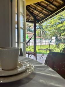 a cup of coffee sitting on a table in front of a porch at Sol & Aconchego Paraty in Paraty
