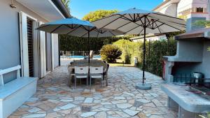 a patio with a table and two umbrellas at Casa delle famiglie in Isola Albarella