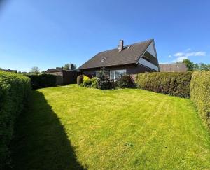 una casa con un gran césped frente a una casa en Ferienhaus Janßen, en Esens 19 fotos más
