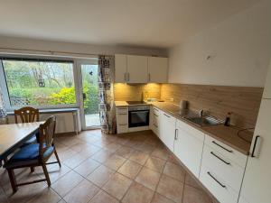 cocina con armarios blancos, mesa y ventana en Ferienhaus Janßen, en Esens