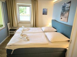 a bedroom with two beds with white sheets and a window at Appartementhaus mit Meerblick und Balkon in Göhren HMLi in Göhren