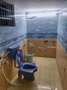 a bathroom with a blue toilet and a painting of a beach at Yal Homestay in Yercaud