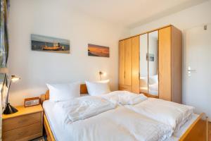 une chambre avec un grand lit avec des draps blancs dans l'établissement Haus am Buchenpark 09, à Neuhof 3 autres photos