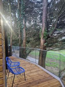 a deck with a blue chair and a tree at Ty Branwen- Luxury Woodland Lodge with Stunning Views in Cowbridge