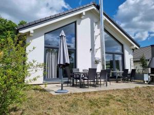 a white house with a table and an umbrella at Ferienhaus Holunderweg an der Theme Obernsees mit Sauna in Truppach