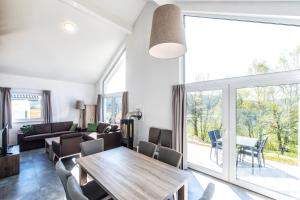 a living room with a wooden table and a large window at Ferienhaus Holunderweg an der Theme Obernsees mit Sauna in Truppach +2 photos