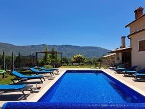 a swimming pool with lounge chairs next to a house at Activity and familiy Villa Milena with heated pool in Kršan