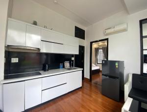 a kitchen with white cabinets and a black refrigerator at Han Riverside in Da Nang