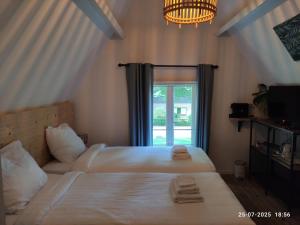 twee bedden in een kamer met een raam bij 't Wapen van Middelie in Middelie