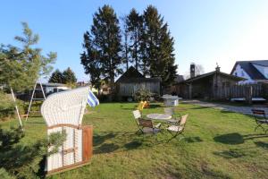 a backyard with a grill and chairs and a table at Am Rieck - Ferienhaus "GR 1904" in Zempin