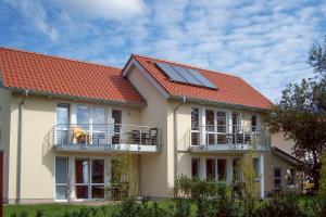 a house with an orange roof with a dog on a balcony at Ab ins Inselglück OG 3a in Bansin