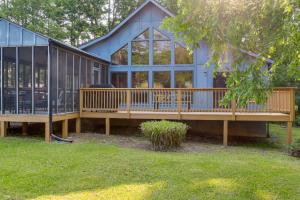 une grande maison bleue avec une grande terrasse dans l'établissement Pool Access Peaceful Cabin in The Woods Resort!, à Hedgesville