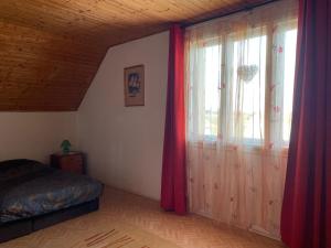 a bedroom with a bed and a window with curtains at VIL'LAGUNA Apartment with view of Balaton in Zánka
