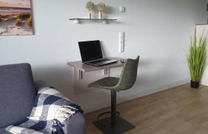 Hohen WieschendorfにあるFerienwohnung "Sunset Fairway 2"のソファの横の机に座ったラップトップコンピュータ