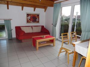 Una sala de estar con un sofá rojo y una mesa. en Helena am Badesee, Ferienhaus, en Aurich