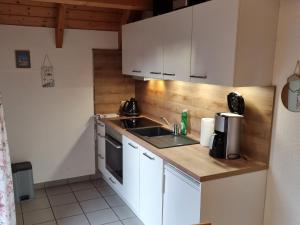 Una cocina con gabinetes blancos y un fregadero. en Helena am Badesee, Ferienhaus, en Aurich 9 fotos más