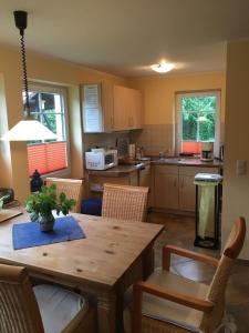 een keuken met een houten tafel en stoelen en een eetkamer bij Ferienhaus zur Kranichweide in Bodstedt