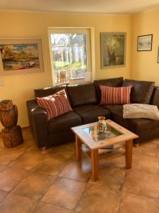 een woonkamer met een leren bank en een salontafel bij Ferienhaus zur Kranichweide in Bodstedt