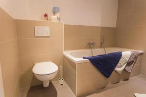 a bathroom with a toilet and a tub and a sink at Das Backsteinhus, App Achtern Diek in Dargen +39 photos
