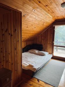 Un dormitorio con una cama en una cabaña de madera. en Domek w lesie, en Radogoszcz