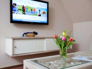 a vase of flowers on a glass table with a tv at Ferienwohnungen Hinrichs in Carolinensiel +55 photos