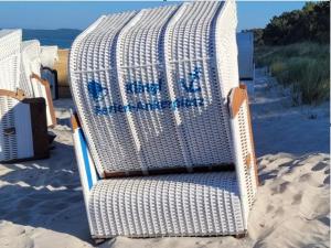 - une chaise en osier blanc assise sur la plage dans l'établissement Haus Zudar FeWo 03 Ferien-Ankerplatz in Prora", à Prora