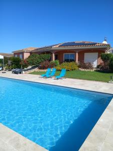 una piscina con dos sillas y una casa en Chez Rachel chambre et salle bain privative chez l'habitant, en Aléria