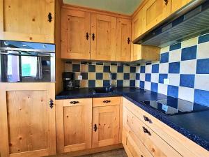a kitchen with wooden cabinets and blue and white tiles at Appartement cosy, 6 pers., pieds des pistes, 2 chambres, balcon sud-ouest, quartier Reberty 1850 - FR-1-452-16 in Les Menuires +12 photos