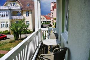 eine Veranda mit 2 Stühlen und einem Tisch auf dem Balkon in der Unterkunft Fewo Rosenhof 04 in Kühlungsborn + 8 Fotos