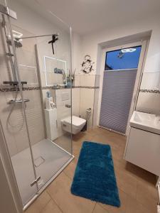 a bathroom with a shower and a toilet and a blue rug at Ferienwohnungen Heimathafen und Hafenkante in Neustadt in Holstein