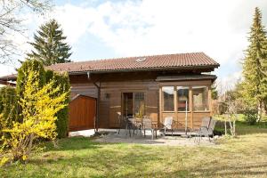 una pequeña casa con una mesa y sillas en un patio en Ferienhaus im Feriendorf Reichenbach B13a, en Nesselwang