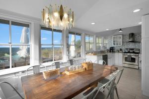 a kitchen with a wooden table with chairs and a chandelier at Diana Luxury Retreat: Private Beach and Vineyards in Wading River