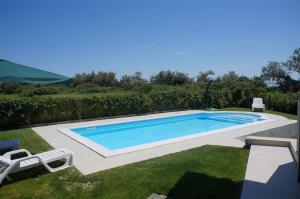 a swimming pool in a yard with two lawn chairs at Maregolf in Isola Albarella