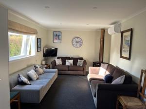 a living room with two couches and a tv at Le Solterre - Akaroa Holiday Home in Akaroa