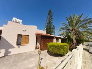 a house with a palm tree in front of it at Seabreeze Villa in Paphos