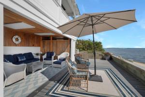 een patio met stoelen, een parasol en water bij Bahia Mar: Beach House, North Fork in Laurel