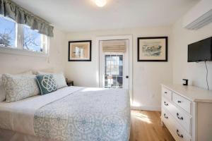 a bedroom with a bed and a dresser and a television at After Dune Delight: Steps to Beach in Wading River