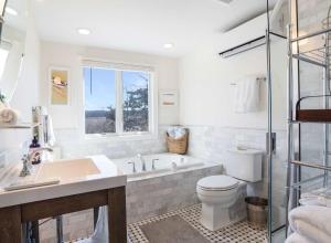 a bathroom with a tub and a toilet and a sink at After Dune Delight: Steps to Beach in Wading River +13 photos