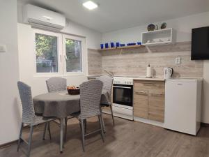 a kitchen with a table and chairs and a white refrigerator at Apartmani Adi in Mostar