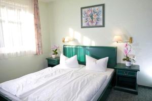 1 Schlafzimmer mit einem Bett mit weißer Bettwäsche und 2 Tischen in der Unterkunft Fewo Rosenhof 02 in Kühlungsborn