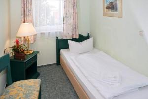 ein Schlafzimmer mit einem Bett und einer Lampe und einem Fenster in der Unterkunft Fewo Rosenhof 02 in Kühlungsborn