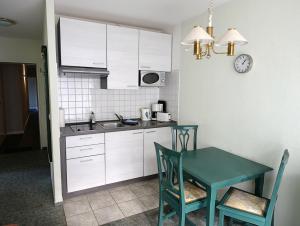 eine Küche mit weißen Schränken und einem Tisch und Stühlen in der Unterkunft Fewo Rosenhof 02 in Kühlungsborn